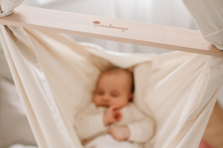 Schlafendes Baby liegend in Babyhängematte WOLLI mit Wunderwiege Logo